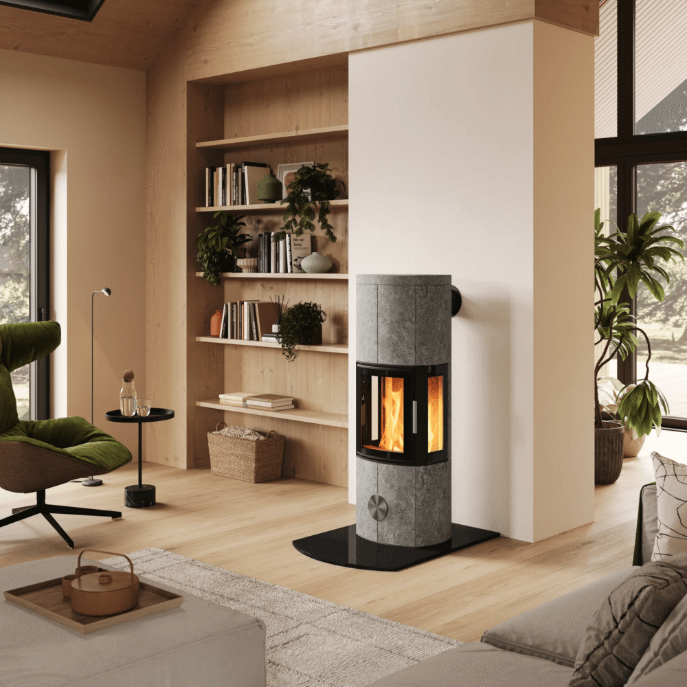 Een moderne speksteenkachel centraal geplaatst in een licht, Scandinavisch interieur met een houten trap, zithoek en koffieset op de voorgrond.