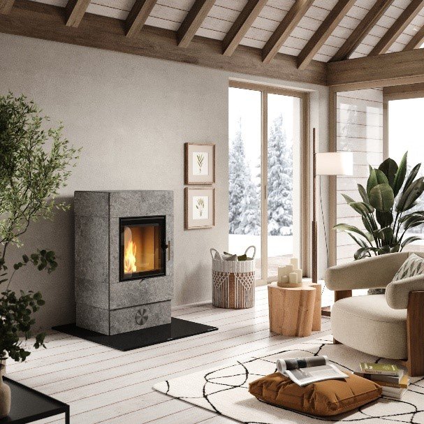 Een gezellige, Scandinavisch ingerichte woonkamer met een Skantherm speksteenkachel als middelpunt, omgeven door natuurlijke materialen en veel licht.